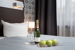 A bed with a bottle of Veuve Clicquot champagne, two glasses, and three green apples on a tray.