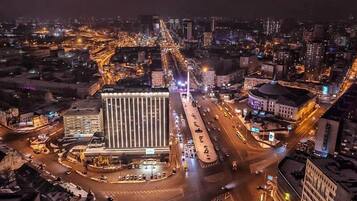 A nighttime cityscape with a prominent building featuring a modern facade and a roundabout with multiple lanes.