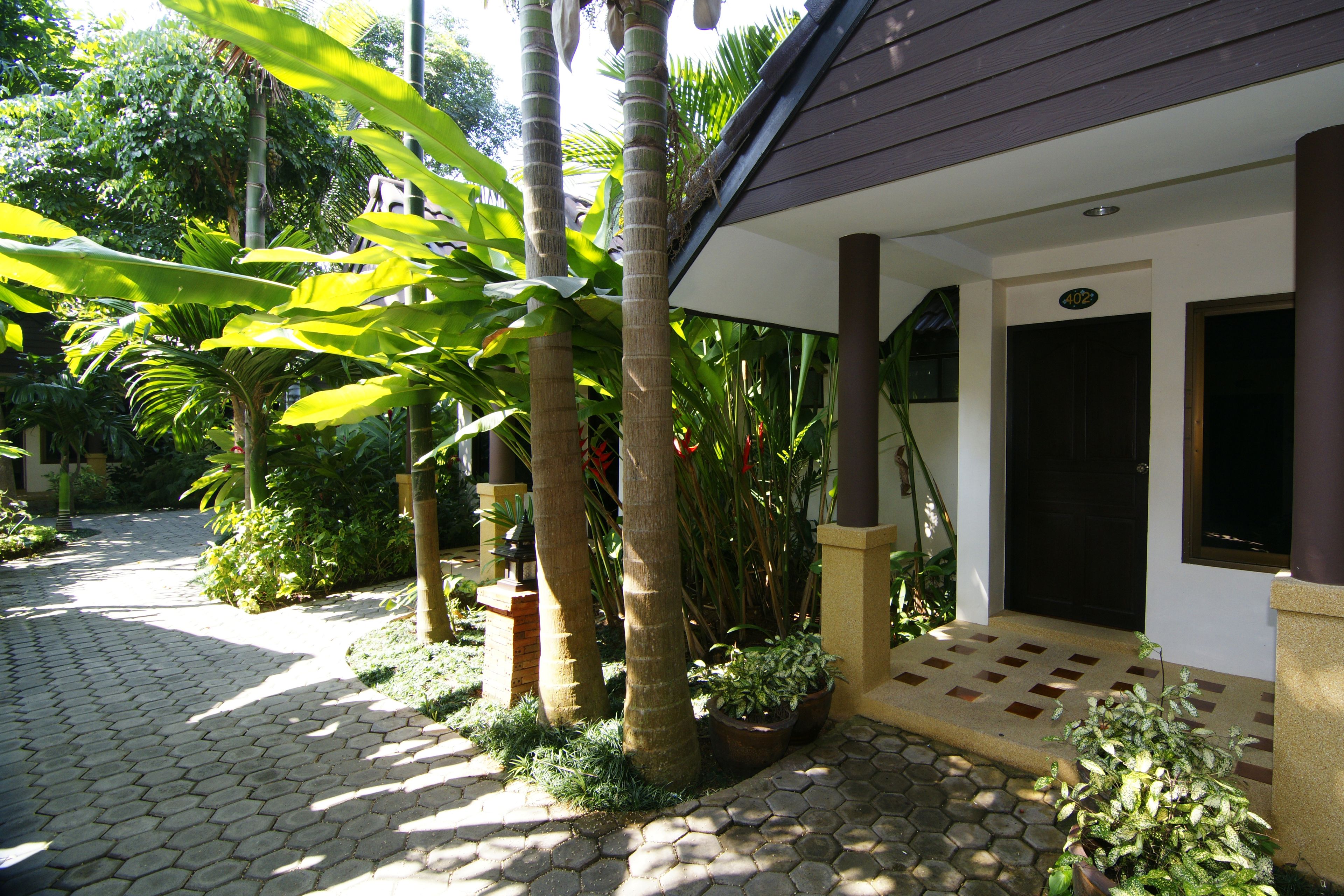 A paved pathway leading to a building with a dark door and a number sign.
