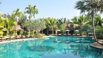 Alberca al aire libre, sombrillas en la alberca y camastros