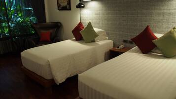 A hotel room with two beds, a chair, a nightstand with a phone, and a painting on the wall.