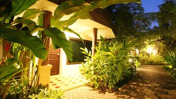 A pathway leading to a building with a tiled entrance and surrounded by lush greenery.