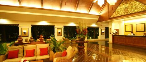 A spacious lobby with a high ceiling, a reception desk, and comfortable seating areas.