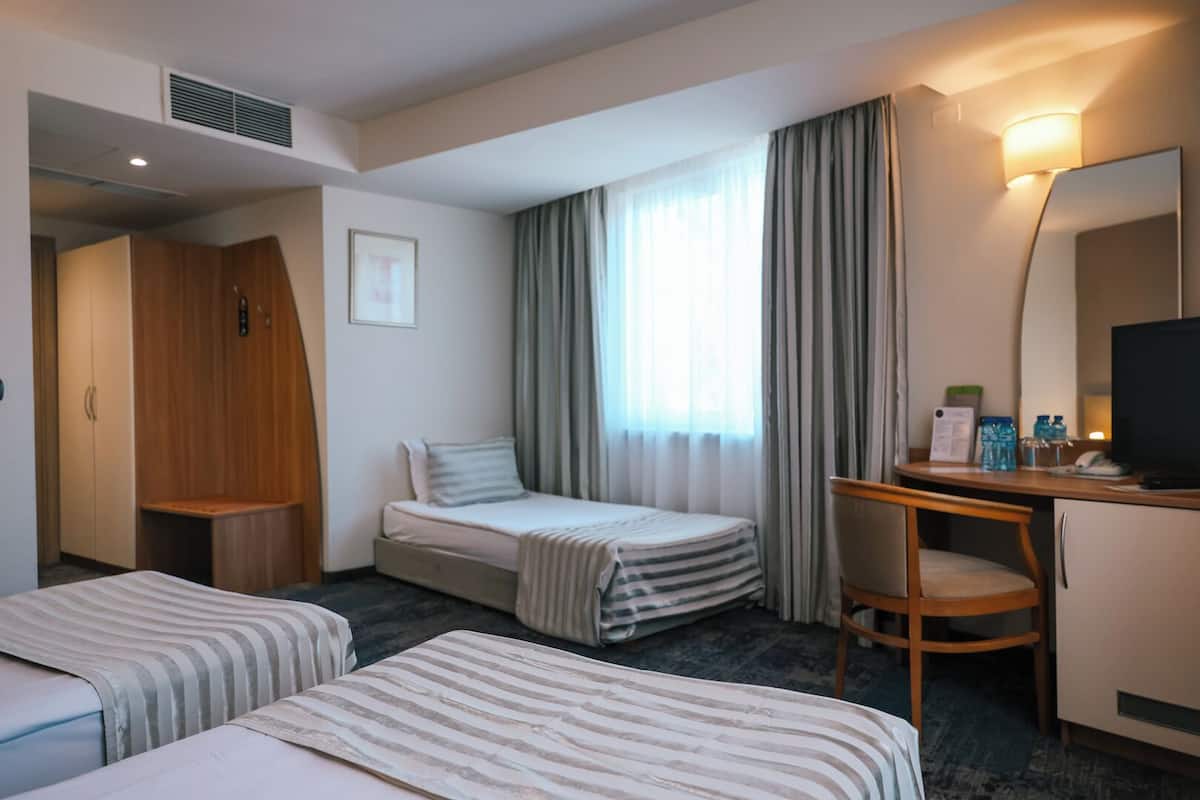 Une chambre d’hôtel avec deux lits, un bureau, une chaise, une télévision et une armoire.
