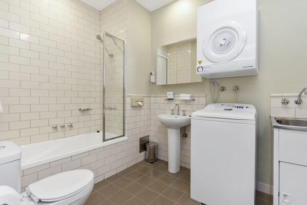 Un baño moderno con bañera, inodoro, lavabo y lavadora.
