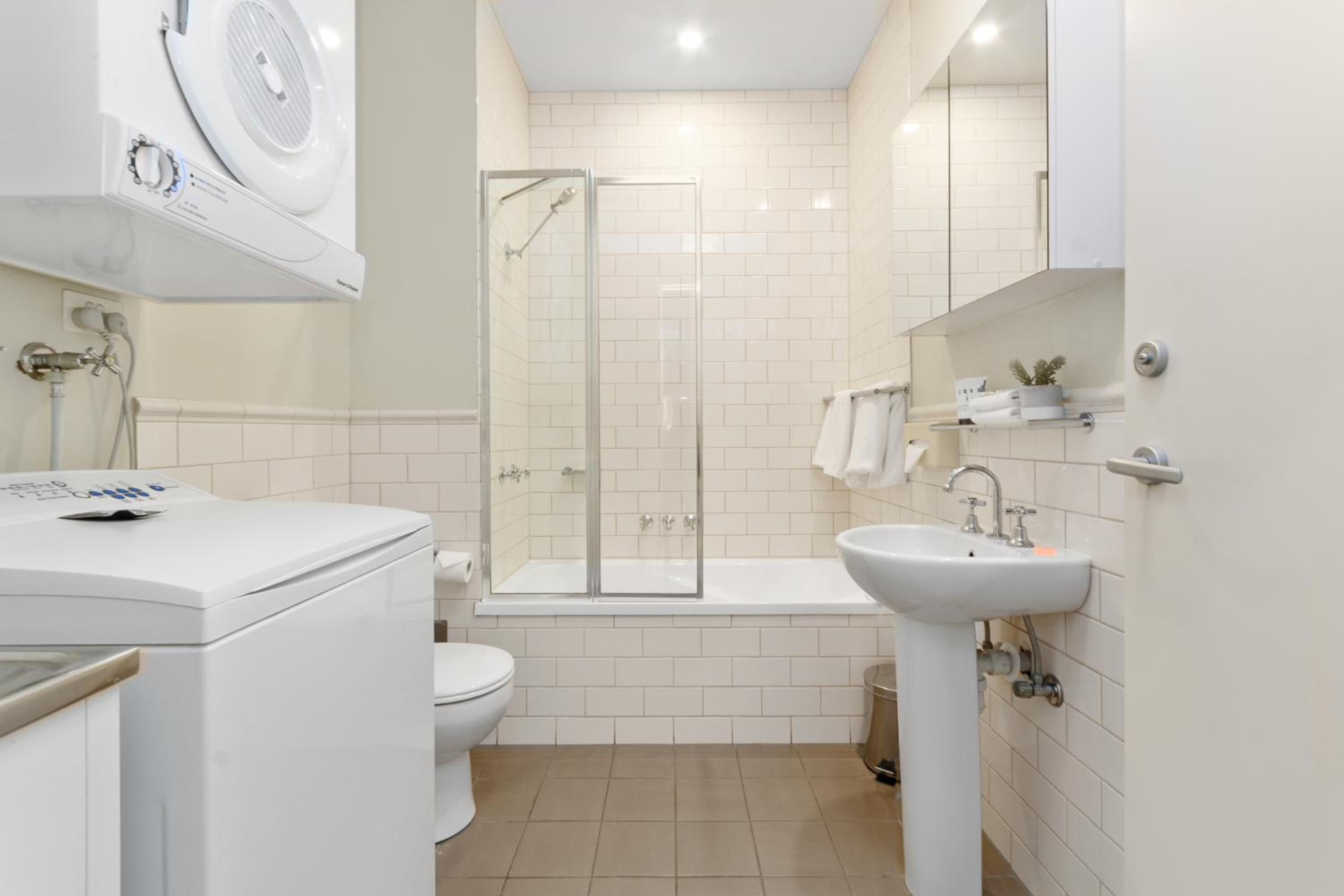 A modern bathroom with a glass-enclosed shower, a white toilet, and a pedestal sink.