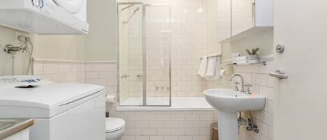 A modern bathroom with a glass-enclosed shower, a white toilet, and a pedestal sink.