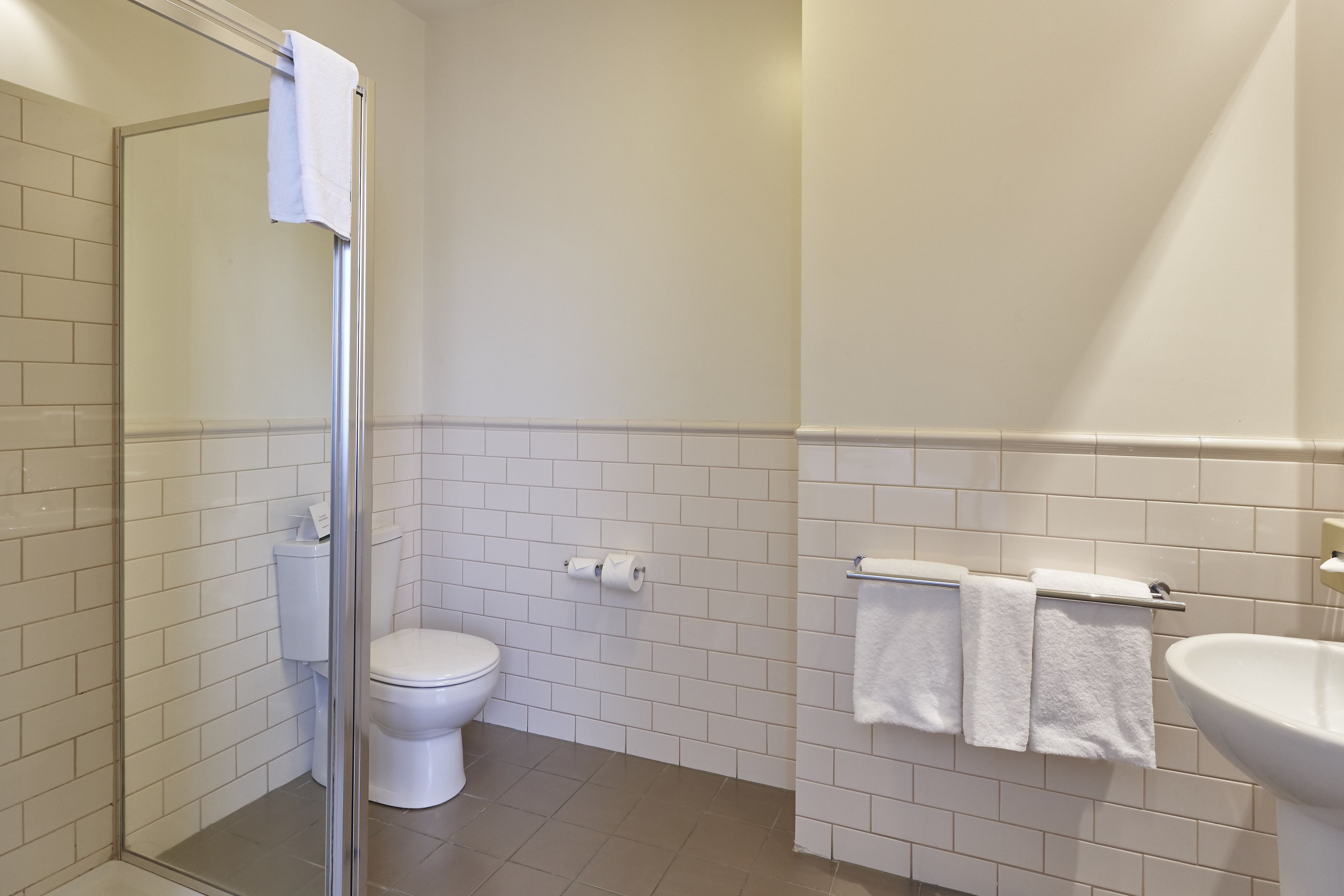 A bathroom with a toilet, a sink, and a glass shower enclosure.