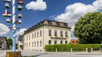 Stunning hotel with a traditional facade, featuring a central entrance and a unique birdhouse-adorned pole.