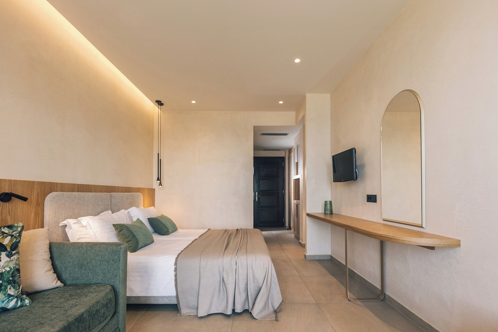 Una habitación de hotel moderna con una cama, una mesita de noche, un televisor y un espejo grande.