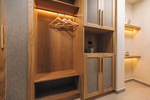 Un armario de madera con varios compartimentos, una barra para colgar ropa y un estante con una planta.