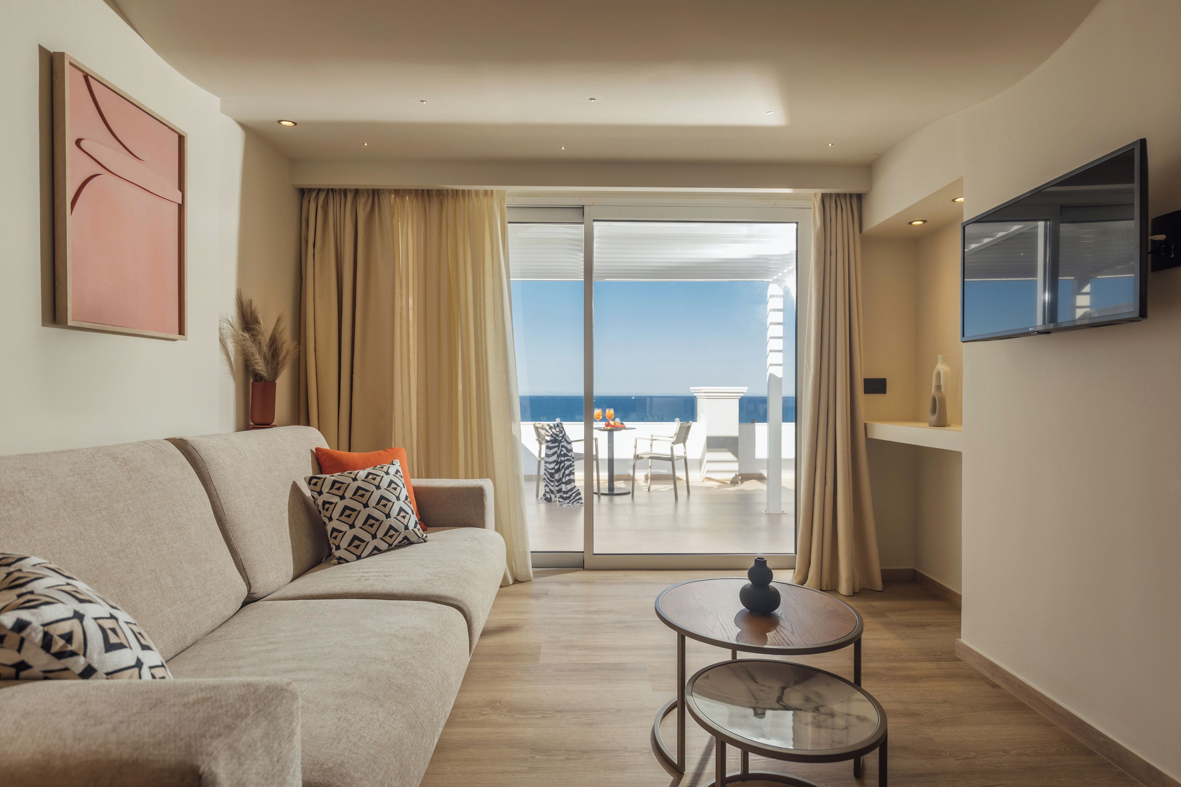 A modern living room with a sofa, a small round table, and a view of the balcony.
