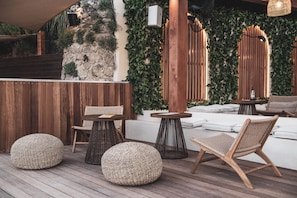 A wooden deck with woven poufs, a wicker chair, and a small table. - Alexandra Beach Resort and Spa (Zakynthos)