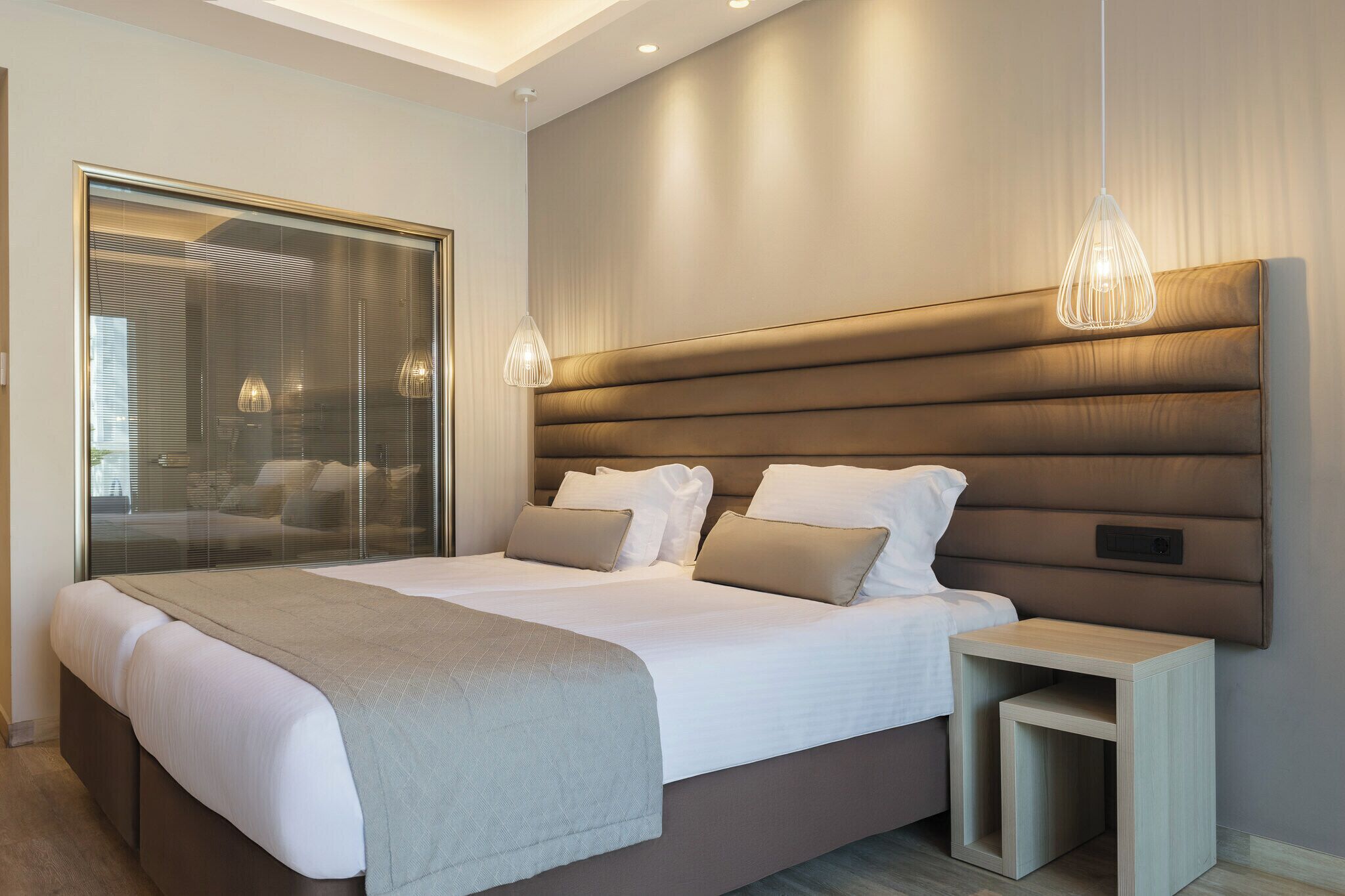 Un dormitorio moderno con una cama grande, mesitas de noche y un separador de vidrio.
