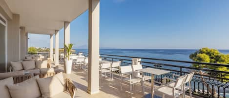 Una terraza con mobiliario exterior, vista al mar y barandilla.