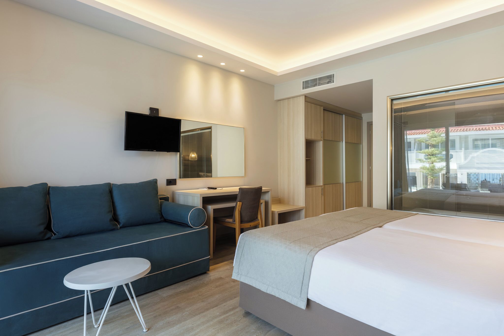 Une chambre d’hôtel moderne équipée d’un lit, d’un bureau, d’un canapé et d’une télévision.