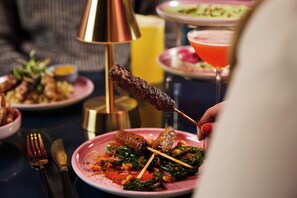 A dining table with plates of food, a candle, and a lamp.