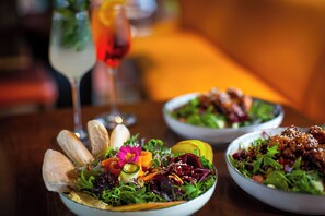 A dining table with three bowls of salad, each with different ingredients and garnishes.