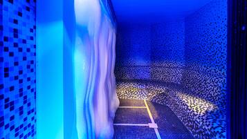 Um quarto com um piso estampado, uma cortina branca e uma parede iluminada em azul.