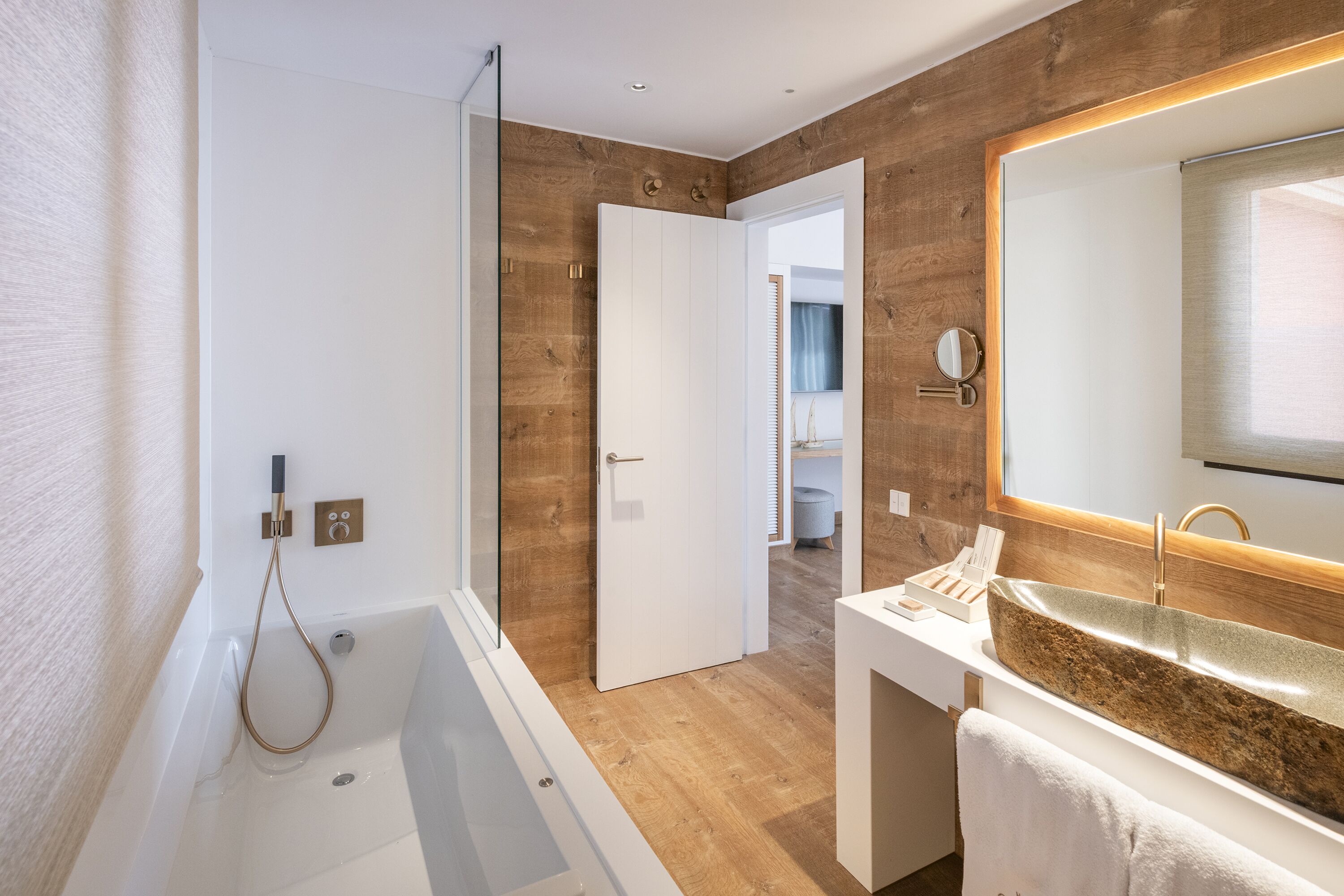 Ein modernes Badezimmer mit Badewanne, Waschbecken und großem Spiegel sowie Holzvertäfelung an den Wänden.