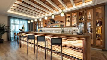 Zona de bar con taburetes de madera, encimera de mármol y techo de madera con vigas a la vista.