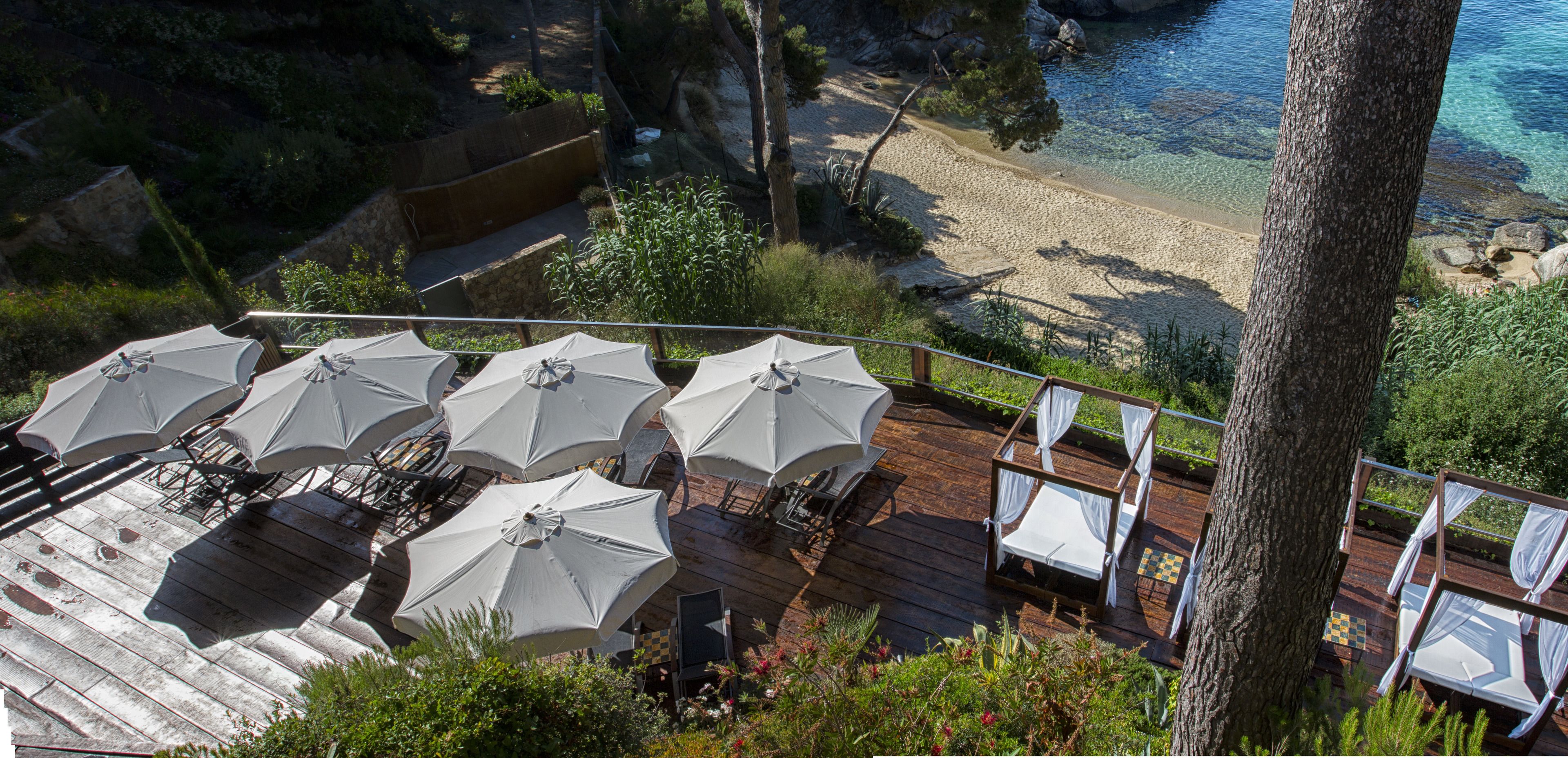 Terraza con mobiliario exterior y sombrillas con vista a la playa.