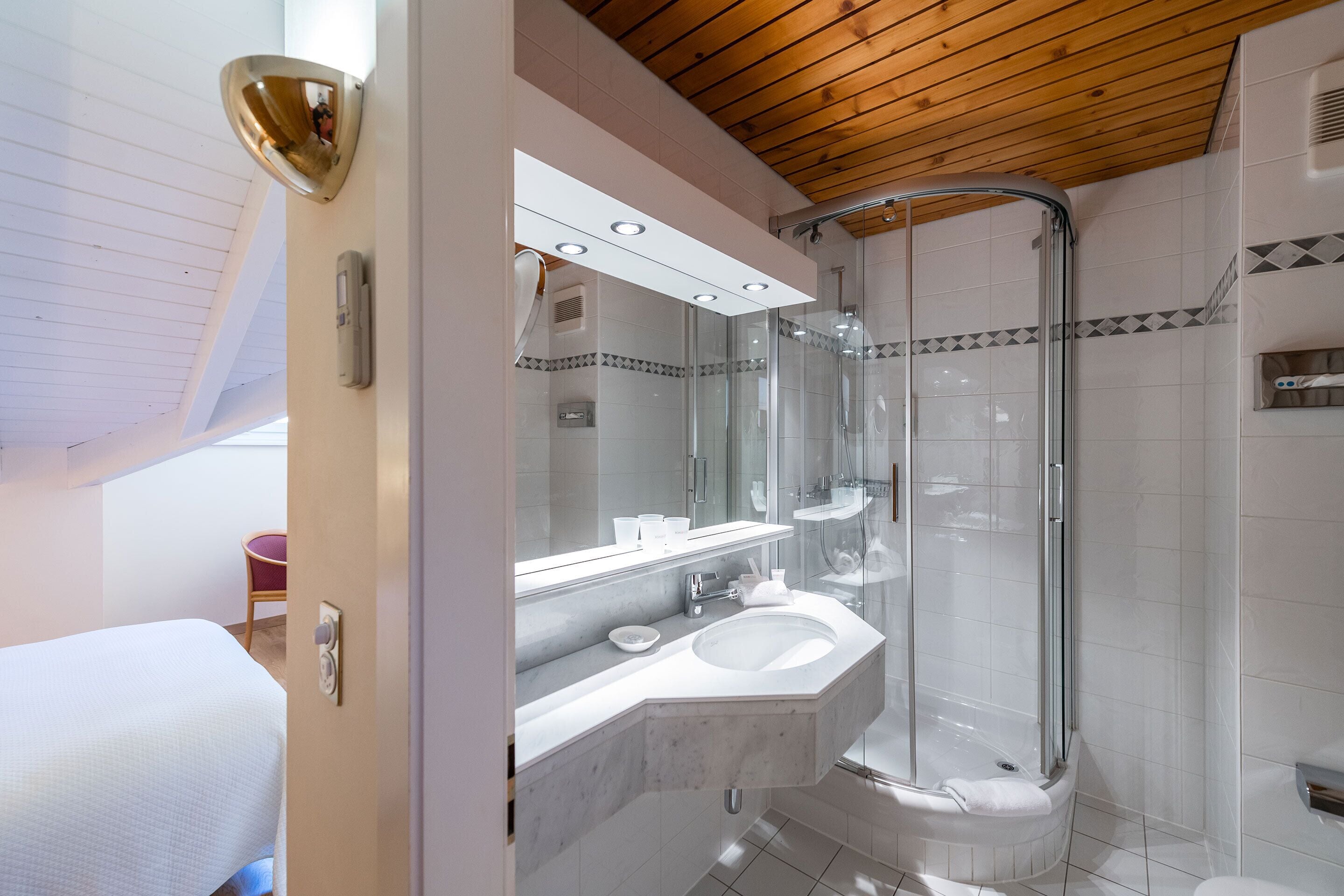 A modern bathroom with a glass-enclosed shower, a white sink, and a mirror above the vanity.