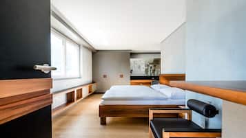 Una habitación de hotel moderna con una cama de madera, un banco y un escritorio pequeño.