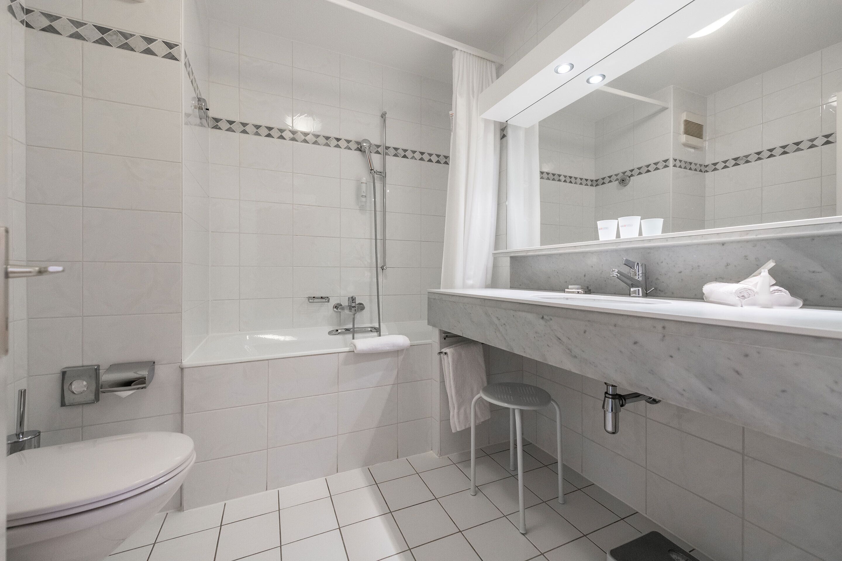 Ein modernes Badezimmer mit Toilette, Badewanne und Dusche.