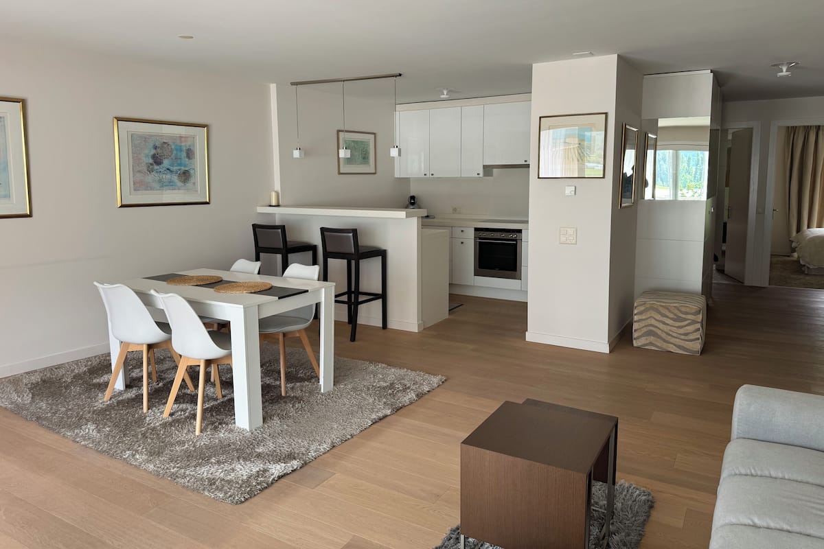 A modern open-plan living area with a dining table, kitchen, and seating area.
