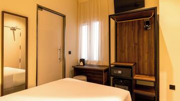 Una habitación de hotel con cama, escritorio, televisor y armario.