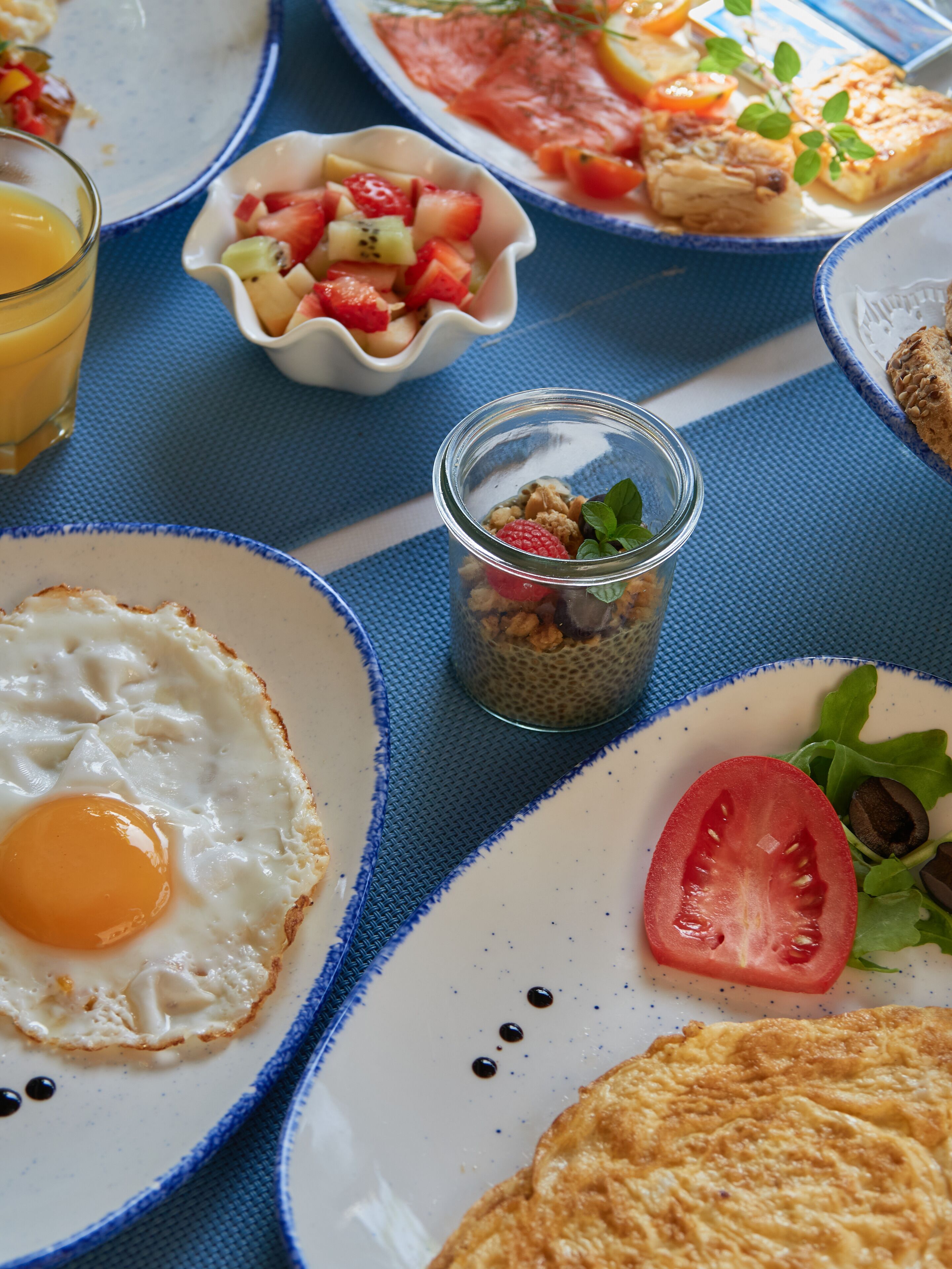 Desayuno con platos de comida, incluyendo huevos, tostadas y una ensalada de frutas.