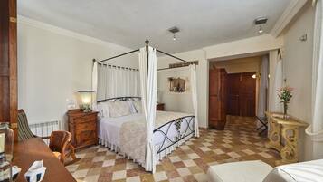 Un dormitorio con cama con dosel, cómoda de madera, una silla y una pequeña mesa con un florero.