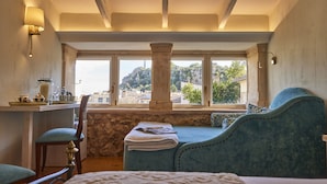 A bedroom with a bed, a chair, a table with a lamp, and a view of a mountain through large windows. - Son Sant Jordi (Pollenca)
