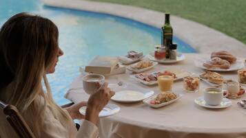 A dining table with breakfast items and a bottle of olive oil.