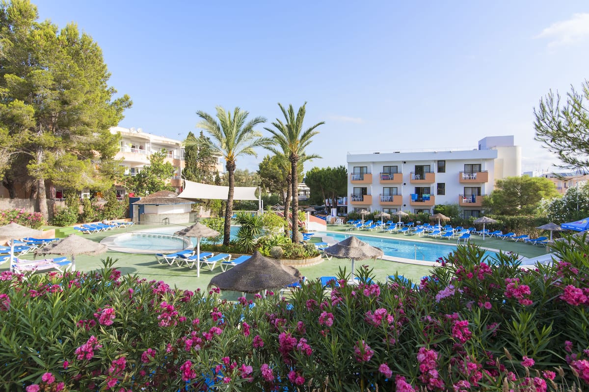 Un resort con piscina, sillas de descanso y un edificio con balcones.