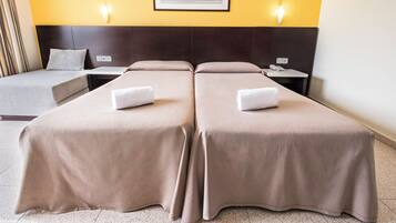 A hotel room with two beds, a nightstand, a bedside table, a framed picture on the wall, and a light switch.