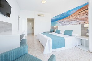 Habitació d'hotel amb un llit, un escriptori, una cadira i un mural gran a la paret.