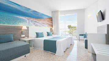 Ein Hotelzimmer mit einem großen Bett, einer Sitzecke, einem Schreibtisch und einem Balkon mit Meerblick.
