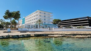Ein mehrstöckiges Hotel mit Balkonen, einem Poolbereich und freiem Blick auf das Meer.