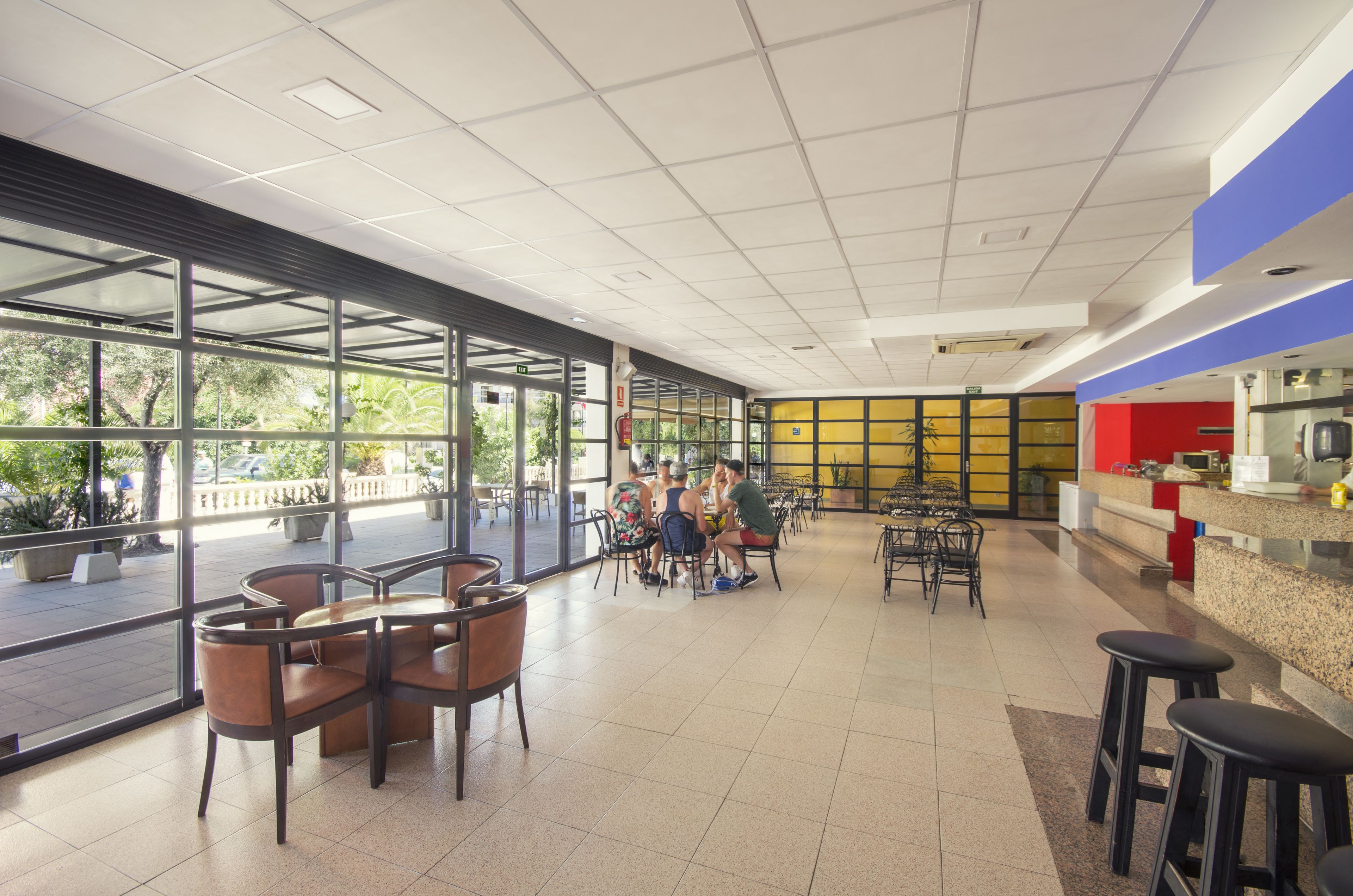 A spacious indoor area with large windows, a counter, and several tables and chairs.