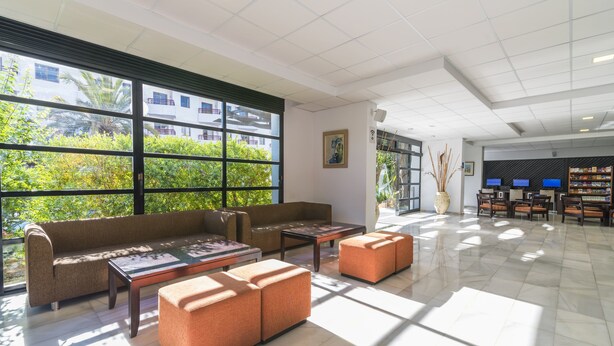 Un hall d’entrée spacieux, doté d’une grande fenêtre, d’un canapé, de poufs et d’un comptoir d’accueil.