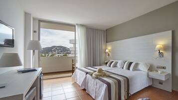 Una habitación de hotel con cama, lámparas de noche, escritorio y televisión.