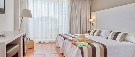 Una habitación de hotel con cama, escritorio, lámpara y ventana con cortinas.