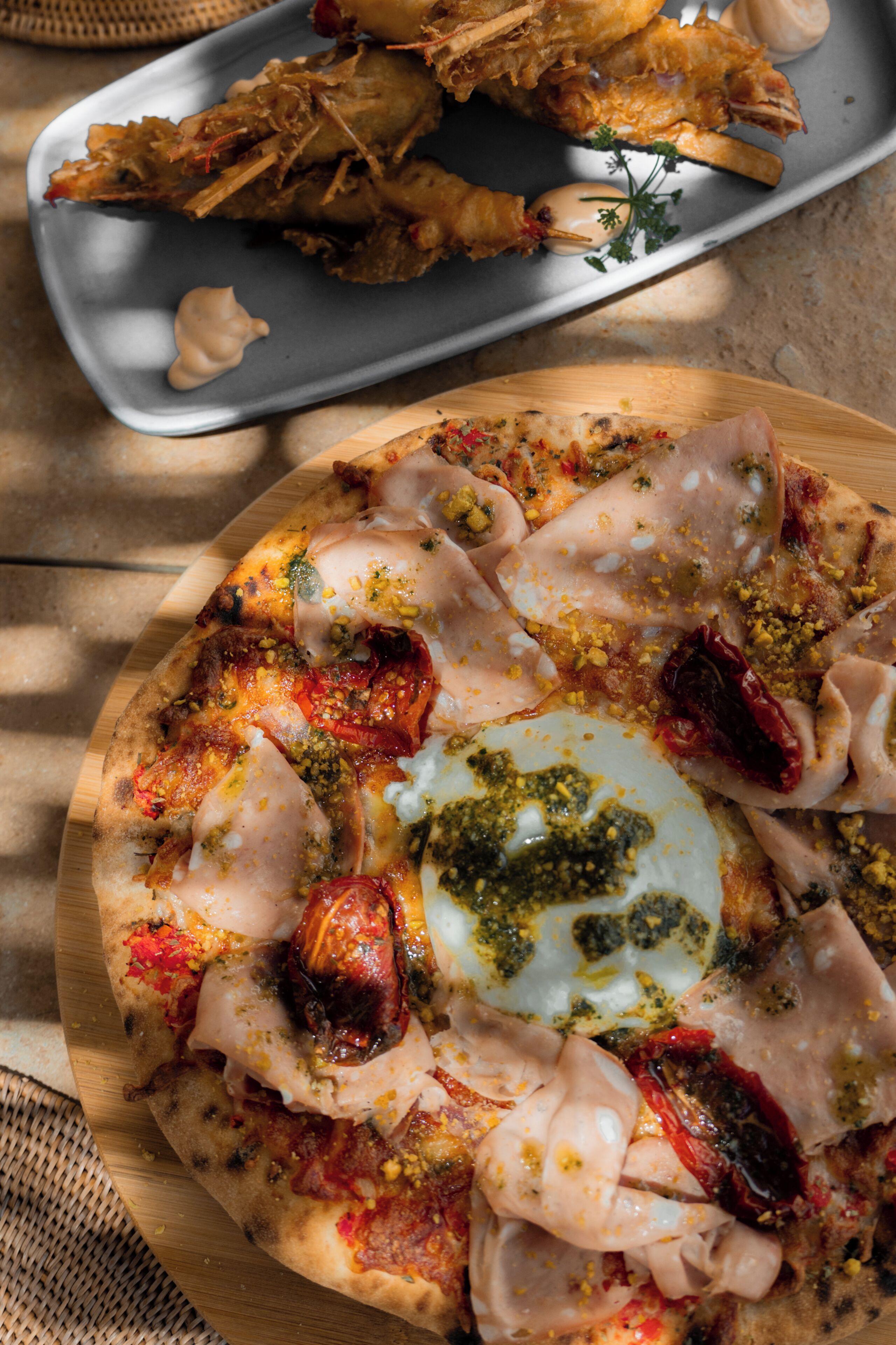 A pizza with various toppings and a side of seafood.