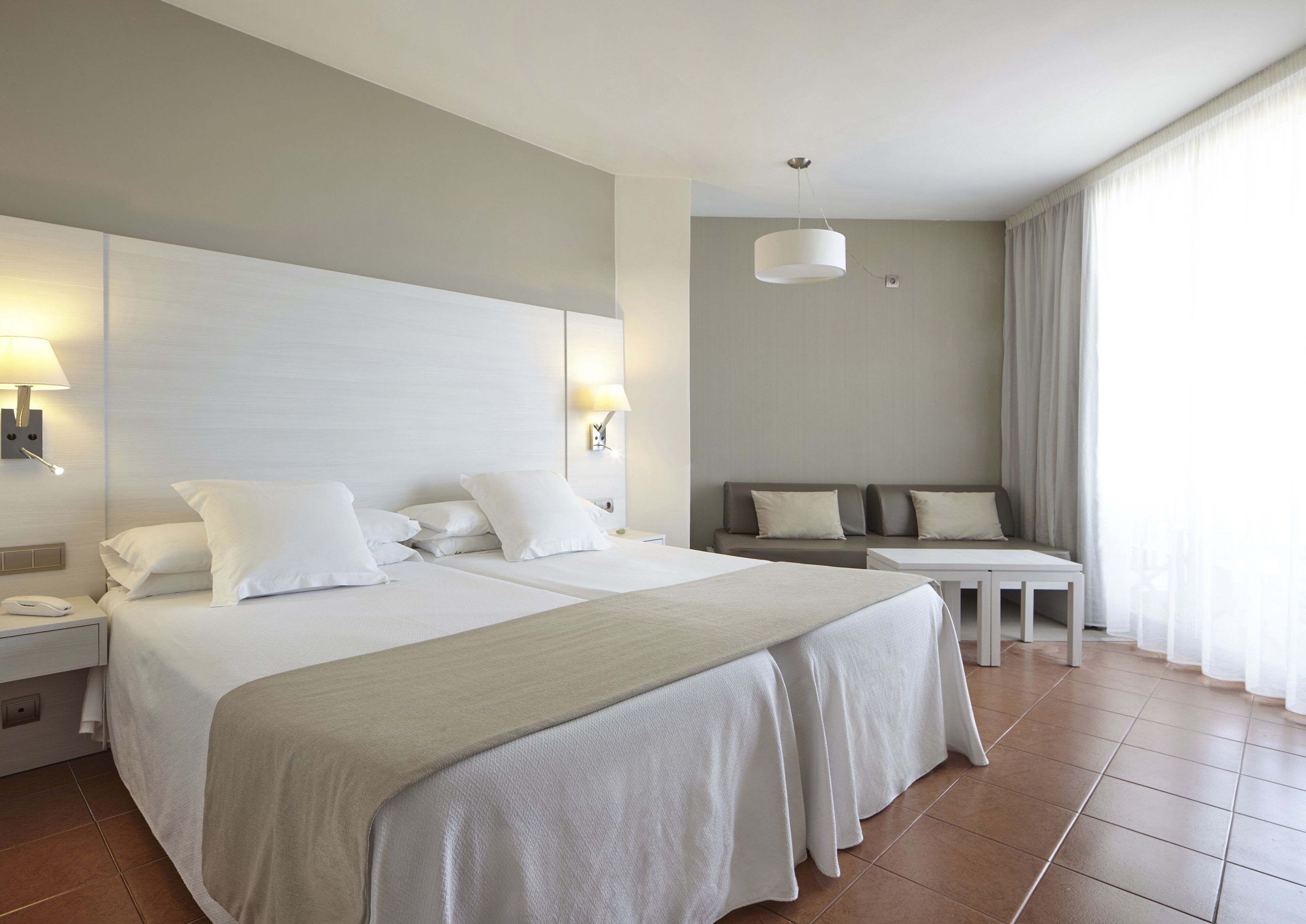 Ein Hotelzimmer mit einem großen Bett, zwei Nachttischen, einer Couch und einem kleinen Tisch.