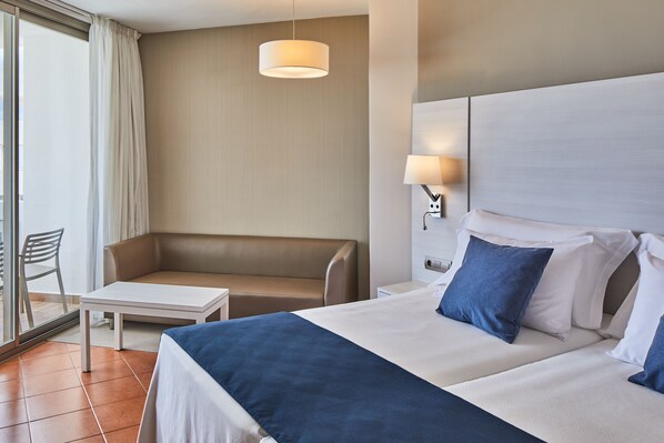 A hotel room with a bed, a sofa, a small table, and a lamp. - Hotel Tres Torres (Santa Eulalia del Rio)