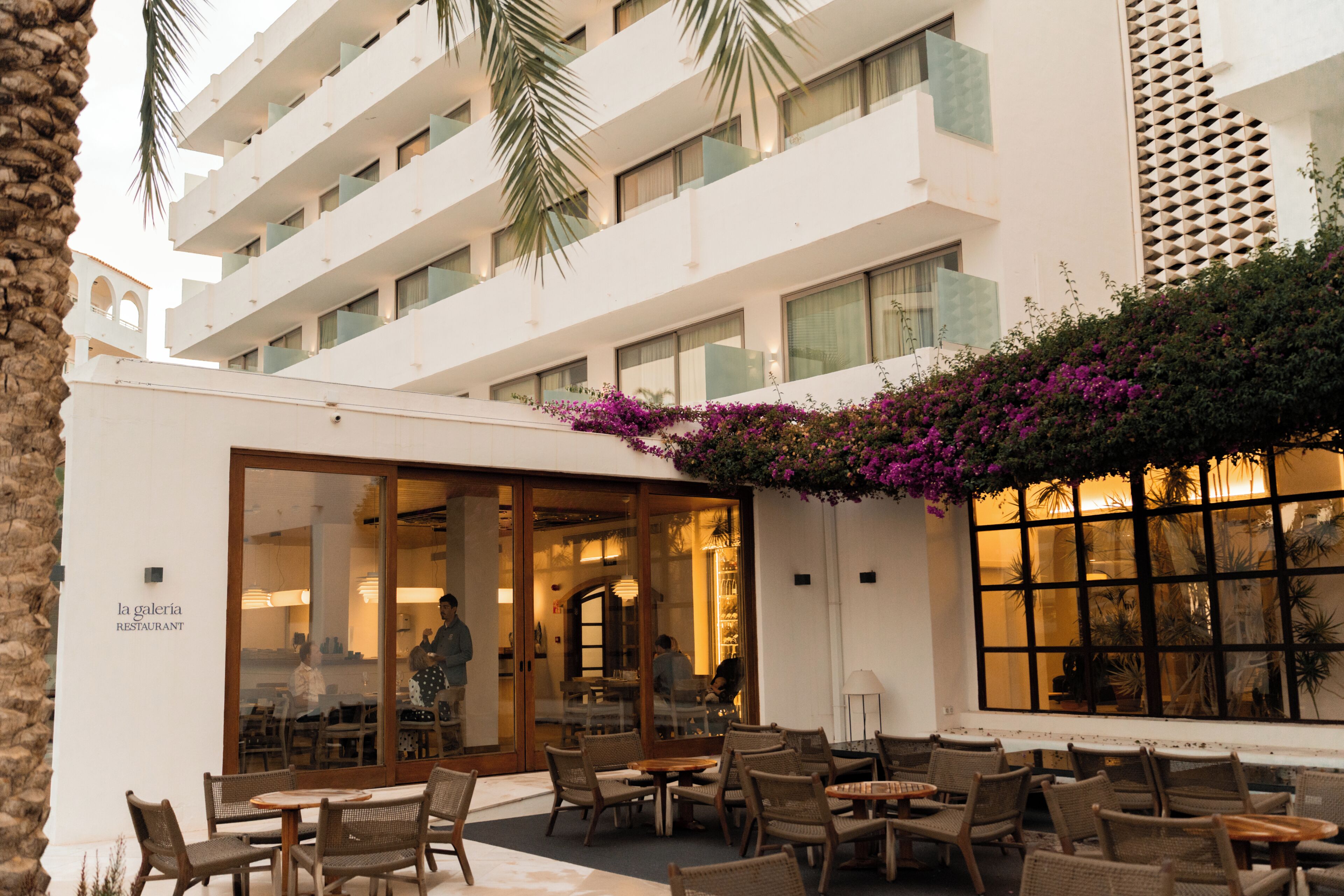 A hotel with outdoor seating, a restaurant, and a view of the building's interior.