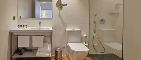 A modern bathroom with a white sink, mirror, toilet, and glass-enclosed shower.