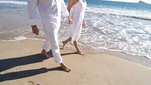 Una pareja caminando sobre una playa arenosa dejando huellas.
